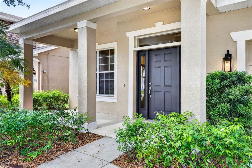 A covered front porch leads to a dark gray front door with a side light — 7906 CAMDEN WOODS DRIVE, TAMPA, FL
