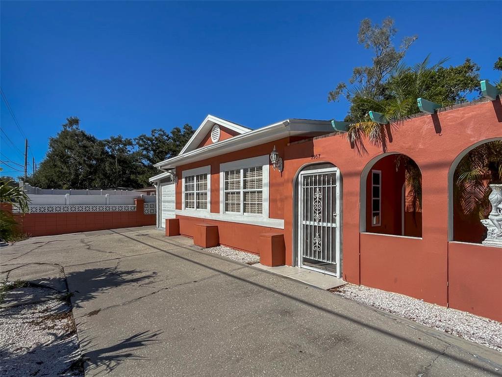 A terracotta-colored house with a white-trimmed front door, arched entryway, and a concrete driveway — 3957 PROCTOR ROAD, SARASOTA, FL