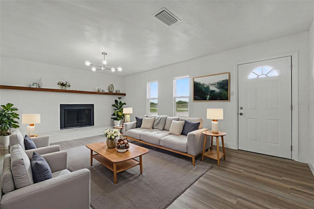 A living room features a fireplace, light wood flooring, and a sofa facing a coffee table — 8812 OAKWOOD DRIVE, LAKE WALES, FL