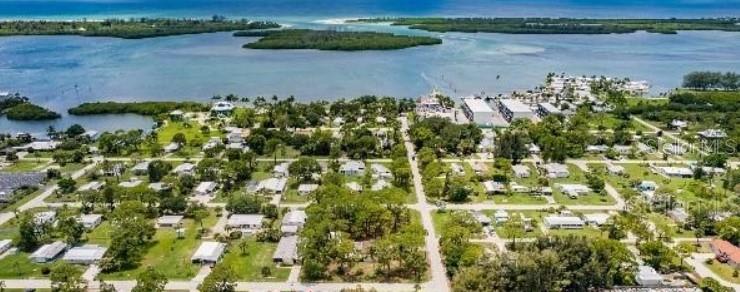 An aerial view shows a coastal neighborhood with houses, trees, and a nearby body of water — 3220 PLACIDA ROAD, ENGLEWOOD, FL