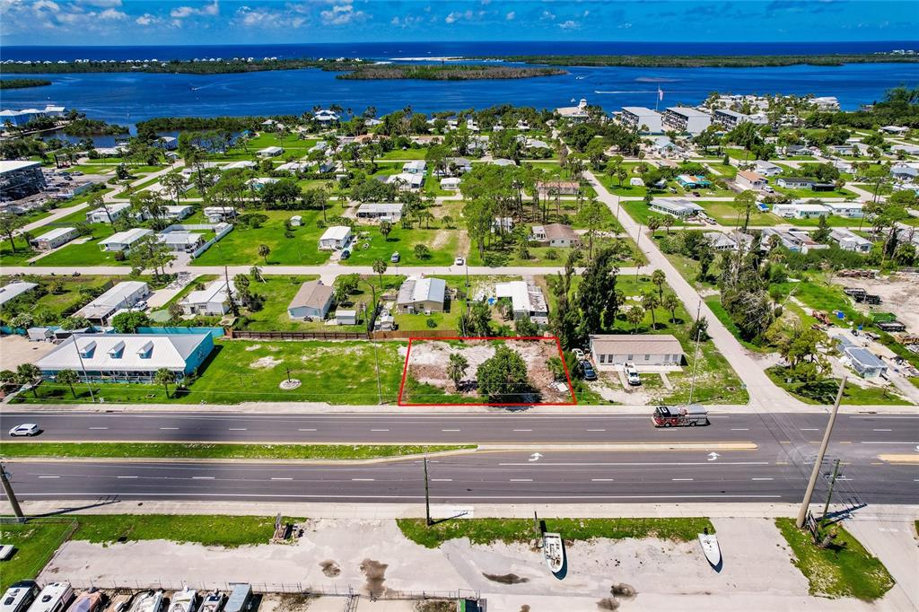 An aerial view shows a vacant, rectangular lot outlined in red along a multi-lane road — 3220 PLACIDA ROAD, ENGLEWOOD, FL