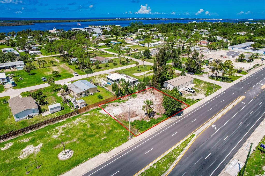 An aerial view shows a vacant, rectangular lot outlined in red next to a highway — 3220 PLACIDA ROAD, ENGLEWOOD, FL