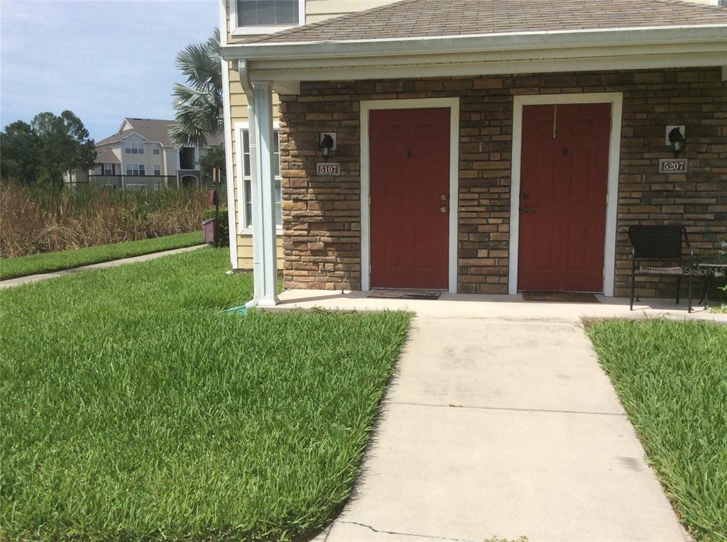 A view of two red front doors on a stone-faced building with a walkway — 4850 51ST STREET W UNIT 5107, BRADENTON, FL