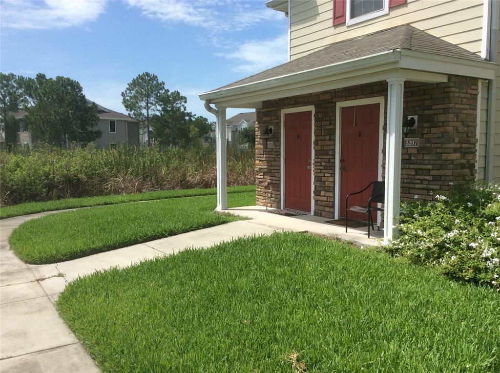 A stone-faced building exterior features two red front doors under a covered porch — 4850 51ST STREET W UNIT 5107, BRADENTON, FL