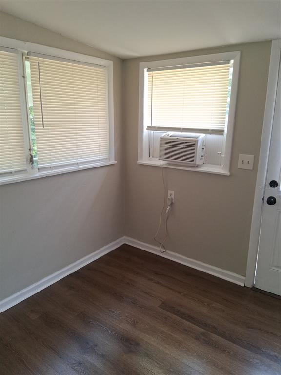 A room with wood-look flooring, beige walls, two windows with blinds, and a window air conditioner — 1123 15TH AVENUE NW UNIT N, LARGO, FL