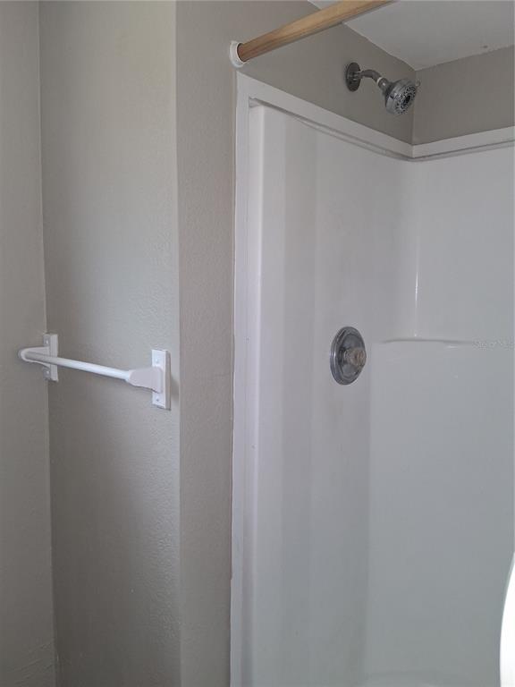 A white shower stall with a chrome showerhead and a wall-mounted towel bar nearby — 1123 15TH AVENUE NW UNIT N, LARGO, FL