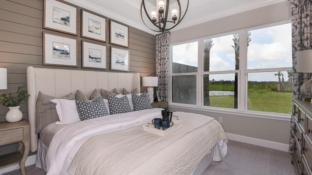 A bedroom features a shiplap accent wall, a tufted headboard, and large windows overlooking greenery — 7528 MOONBEAM AVENUE, SARASOTA, FL