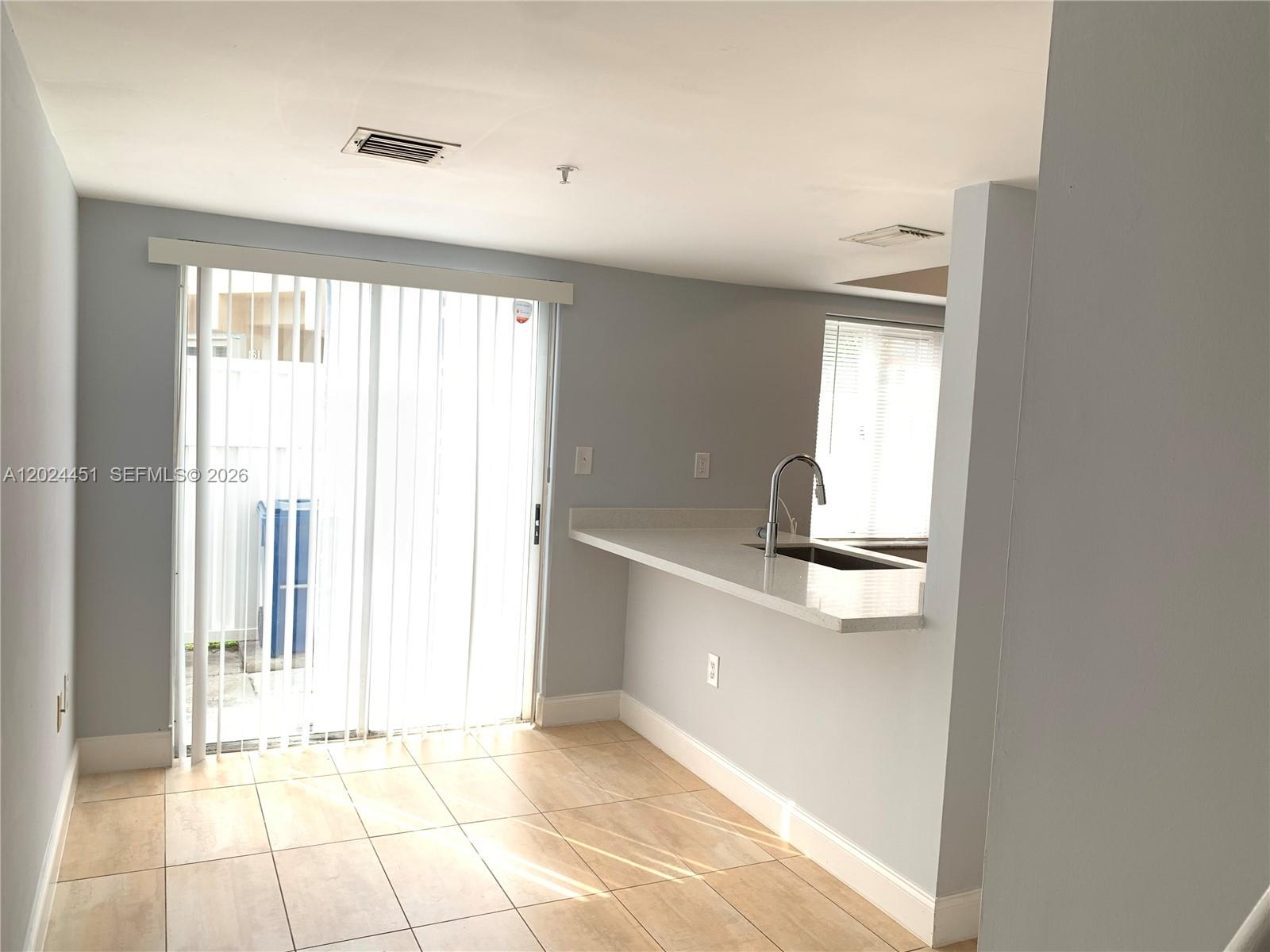 A kitchen features stainless steel appliances, light gray cabinetry, and a stacked washer and dryer — 143 Riviera Cir # 143, Weston FL 33326, WESTON, FL