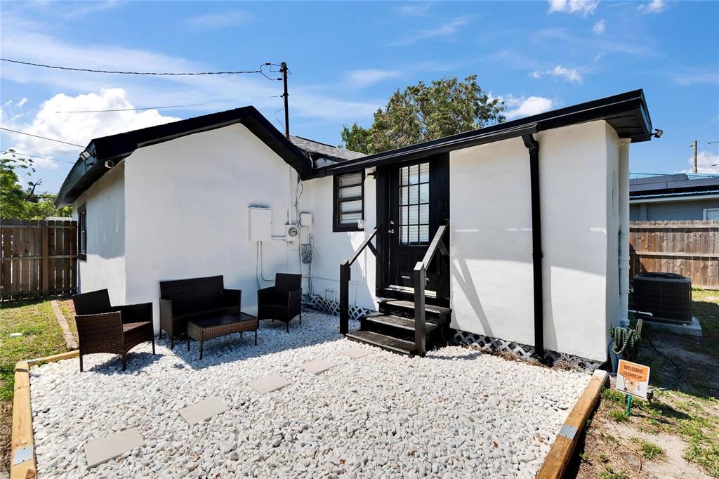 The exterior of a white house features a black door, stairs, and a gravel patio — 1138 HOWARD STREET, CLEARWATER, FL