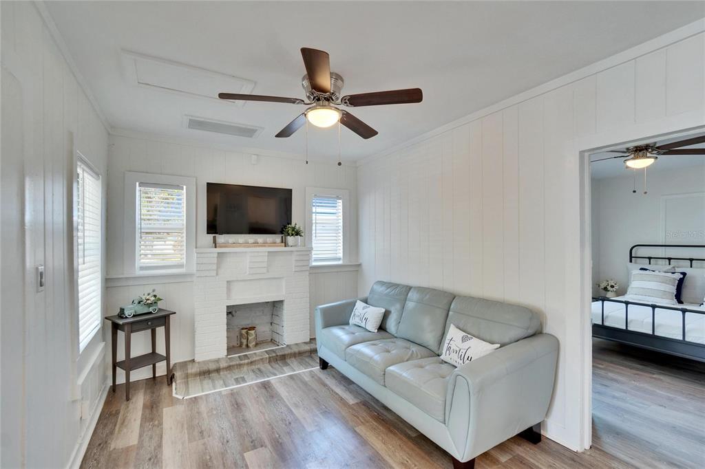 A living room features a white brick fireplace, light gray sofa, and wood-look flooring — 1138 HOWARD STREET, CLEARWATER, FL