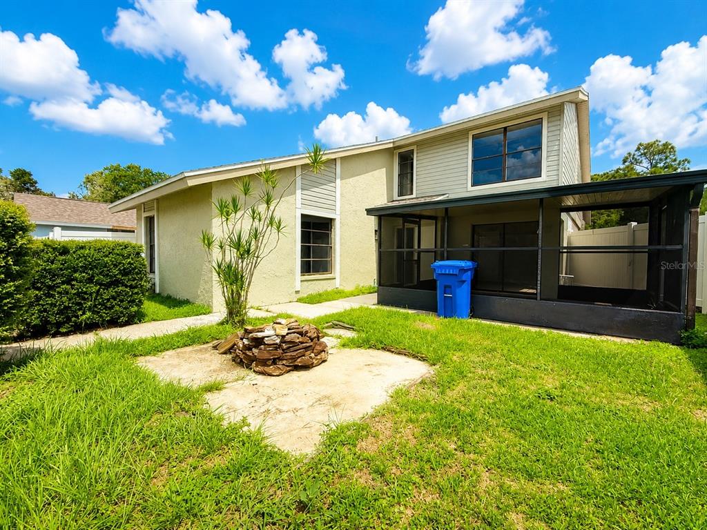 The backyard features a concrete patio with a stone fire pit and a screened-in porch — 5104 SPRINGWATER COURT, TAMPA, FL