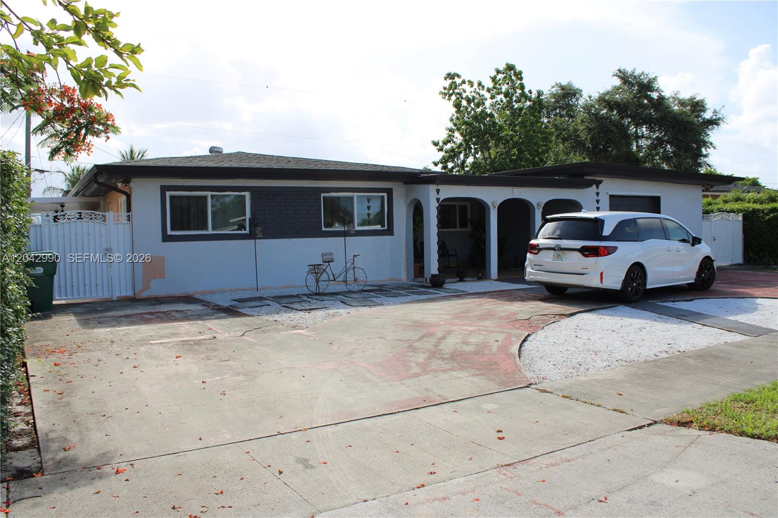 A single-story house with a white exterior, arched entryway, and a paved driveway — 11512 NW 58th Ave, Hialeah FL 33012, HIALEAH, FL