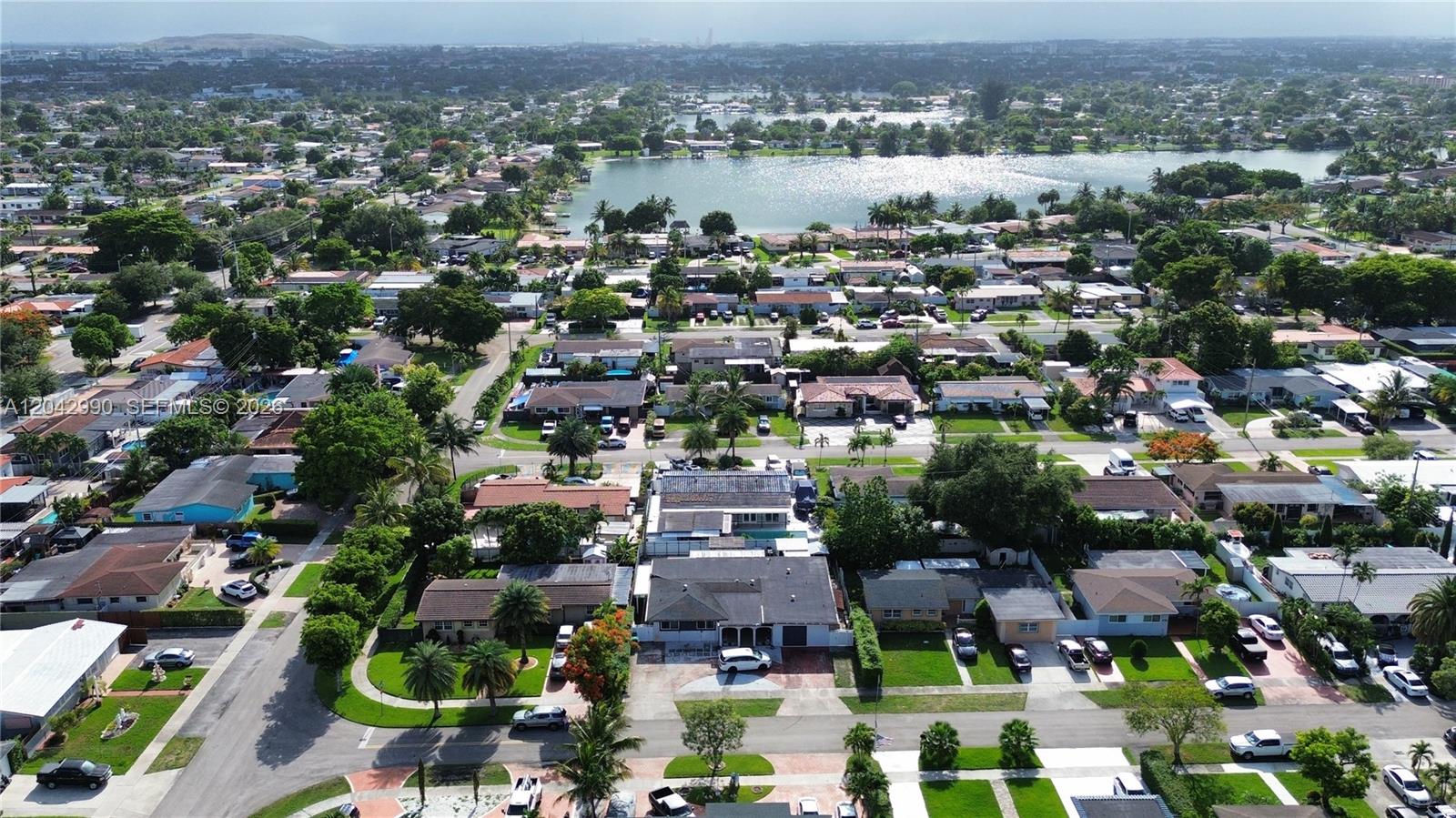 An aerial view shows a suburban neighborhood with houses, streets, and a large lake — 11512 NW 58th Ave, Hialeah FL 33012, HIALEAH, FL