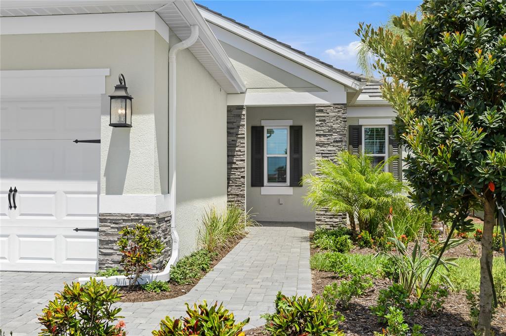 A paved walkway leads to the front entrance of a house with stone accents — 2003 BAMBOO PALM COVE, BRADENTON, FL