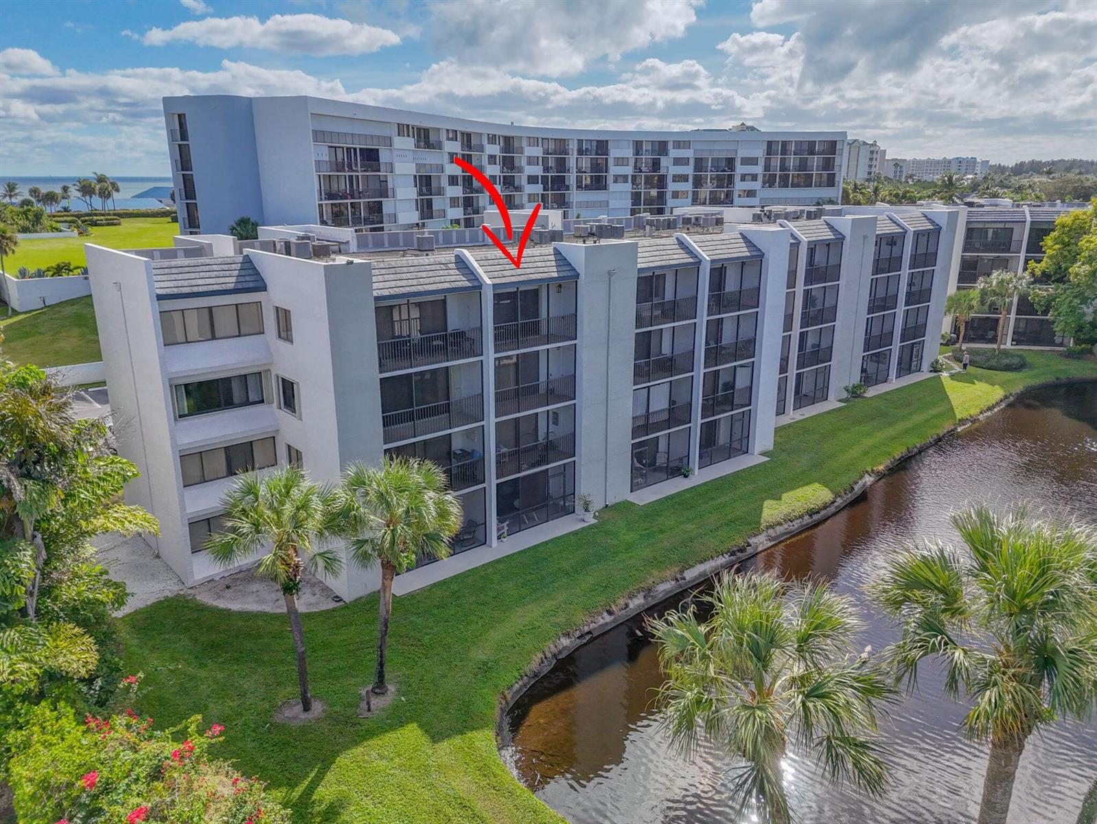 An exterior view of a multi-story apartment building with balconies overlooking a small canal — 1605 S Us Highway 1 # A407, Jupiter FL 33477, JUPITER, FL