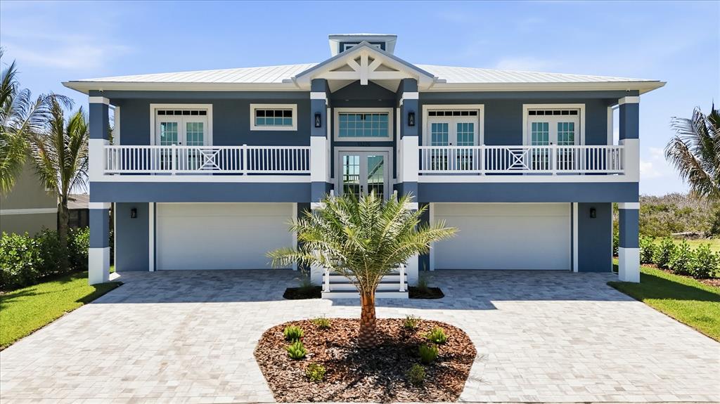 A two-story blue house with a white balcony, metal roof, and two garage doors — 13220 ANGLERS WAY, PLACIDA, FL