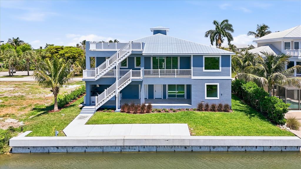 A blue three-story waterfront house features a metal roof, exterior stairs, and a boat lift — 13220 ANGLERS WAY, PLACIDA, FL