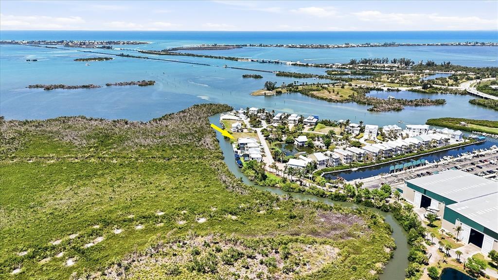An aerial view shows a waterfront residential community bordered by mangroves and a large warehouse — 13220 ANGLERS WAY, PLACIDA, FL