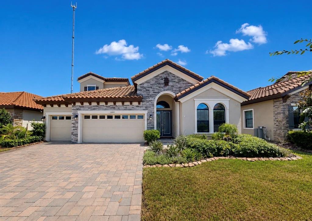 A single-story house with a stone facade, a tiled roof, and a paved driveway — 13712 OSPREY FERN LANE, RIVERVIEW, FL