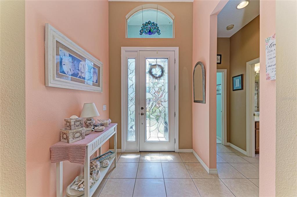A bright entryway features peach walls, tile flooring, a decorative front door, and a console table — 3728 SUMMERWIND CIRCLE, BRADENTON, FL
