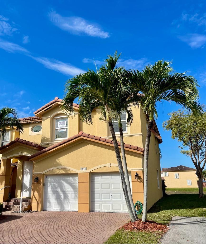 A two-story yellow house with a two-car garage and palm trees in the front yard — 8666 NW 109th Ct # 8666, Doral FL 33178, DORAL, FL