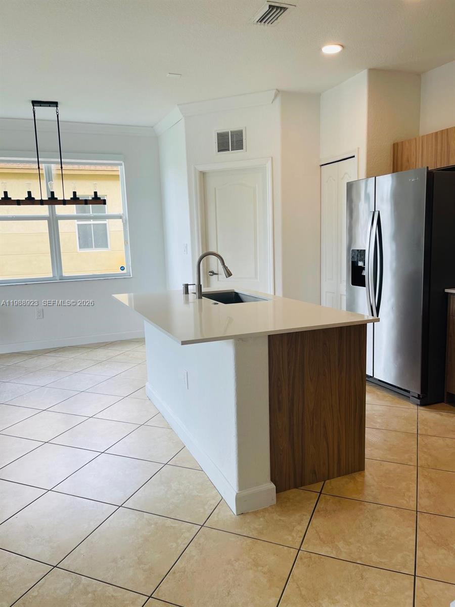 A kitchen features a white island with a sink, stainless steel refrigerator, and tile flooring — 8666 NW 109th Ct # 8666, Doral FL 33178, DORAL, FL