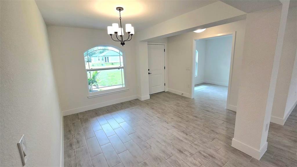 A dining area features light wood-look tile flooring, a chandelier, and an arched window — 2239 N BISCAYNE DRIVE, NORTH PORT, FL