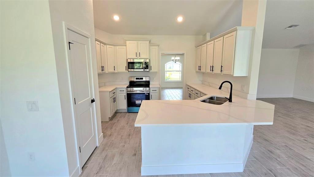 A kitchen features white cabinets, stainless steel appliances, a quartz island, and light-colored tile flooring — 2239 N BISCAYNE DRIVE, NORTH PORT, FL