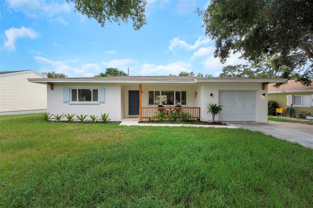 A single-story house with a white exterior, a front porch, and an attached one-car garage — 245 GROVE CIR N, DUNEDIN, FL