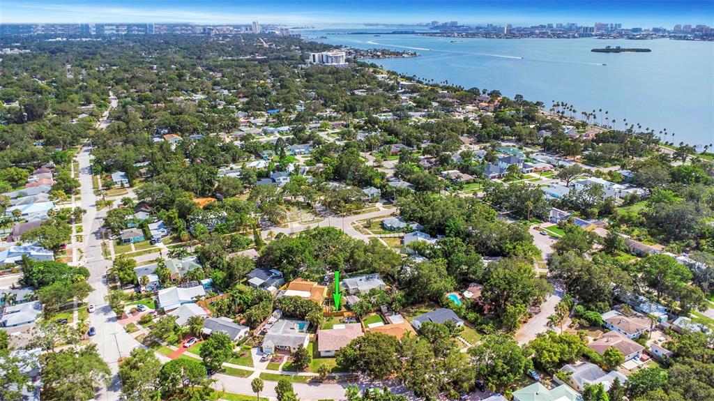An aerial view shows a residential neighborhood with a green arrow pointing to a house — 245 GROVE CIR N, DUNEDIN, FL