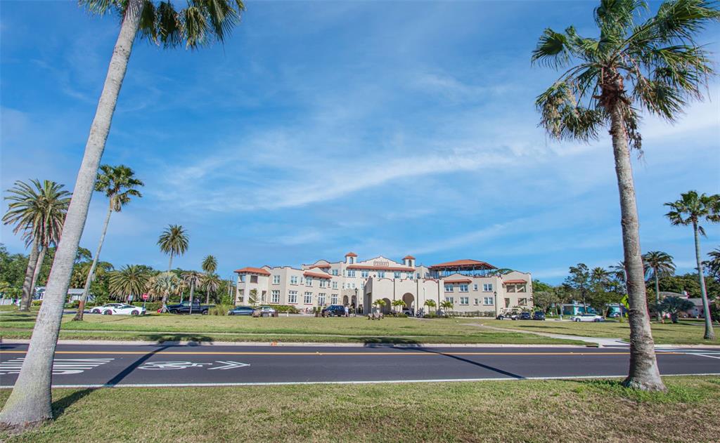A large, multi-story hotel building stands behind a road with palm trees in the foreground — 245 GROVE CIR N, DUNEDIN, FL