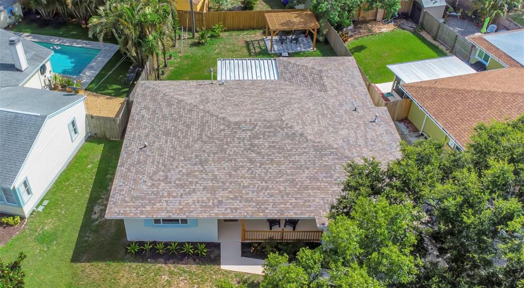 An aerial view shows a house with a shingled roof, a front porch, and a backyard — 245 GROVE CIR N, DUNEDIN, FL