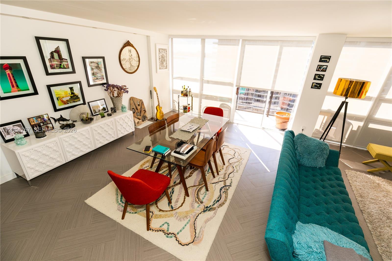 A dining area with a glass table, colorful chairs, and a teal sofa — 600 NE 36th St, Miami FL 33137, MIAMI, FL