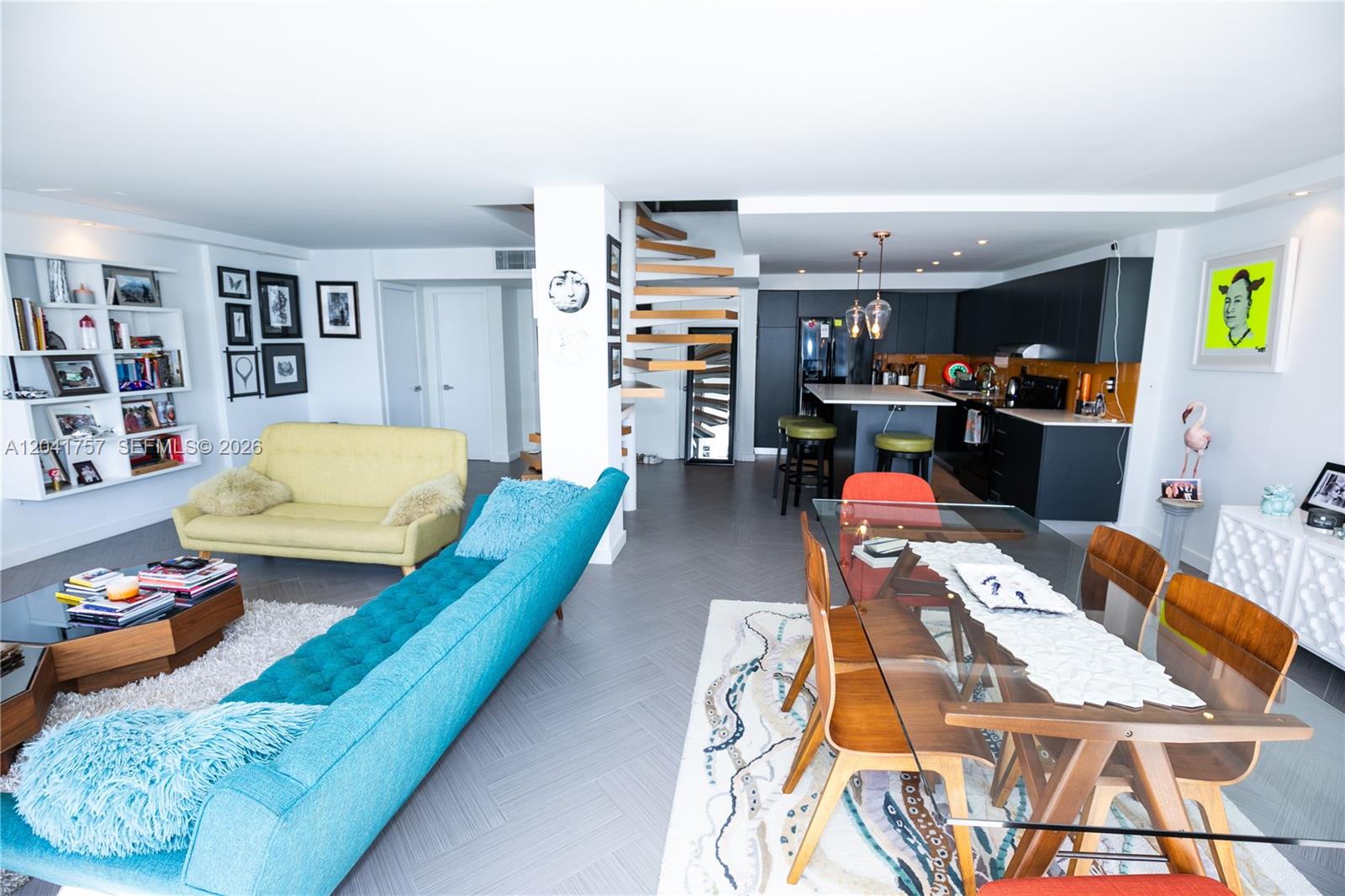 An open-concept living and dining area features a spiral staircase, modern kitchen, and colorful furniture — 600 NE 36th St, Miami FL 33137, MIAMI, FL