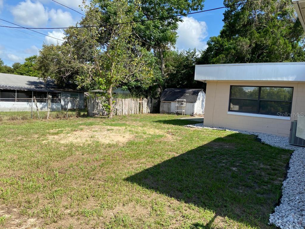 A backyard view features a beige house, a small shed, and a wooden fence — 3408 LEEMOORE PLACE, ORLANDO, FL