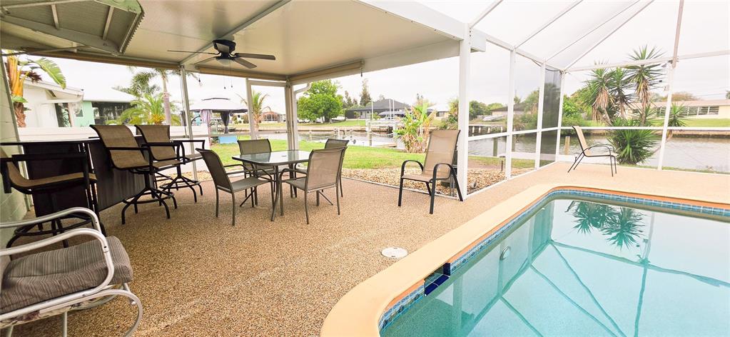 A screened-in patio features a swimming pool, outdoor dining furniture, and a canal view — 392 E TARPON BOULEVARD NW, PORT CHARLOTTE, FL