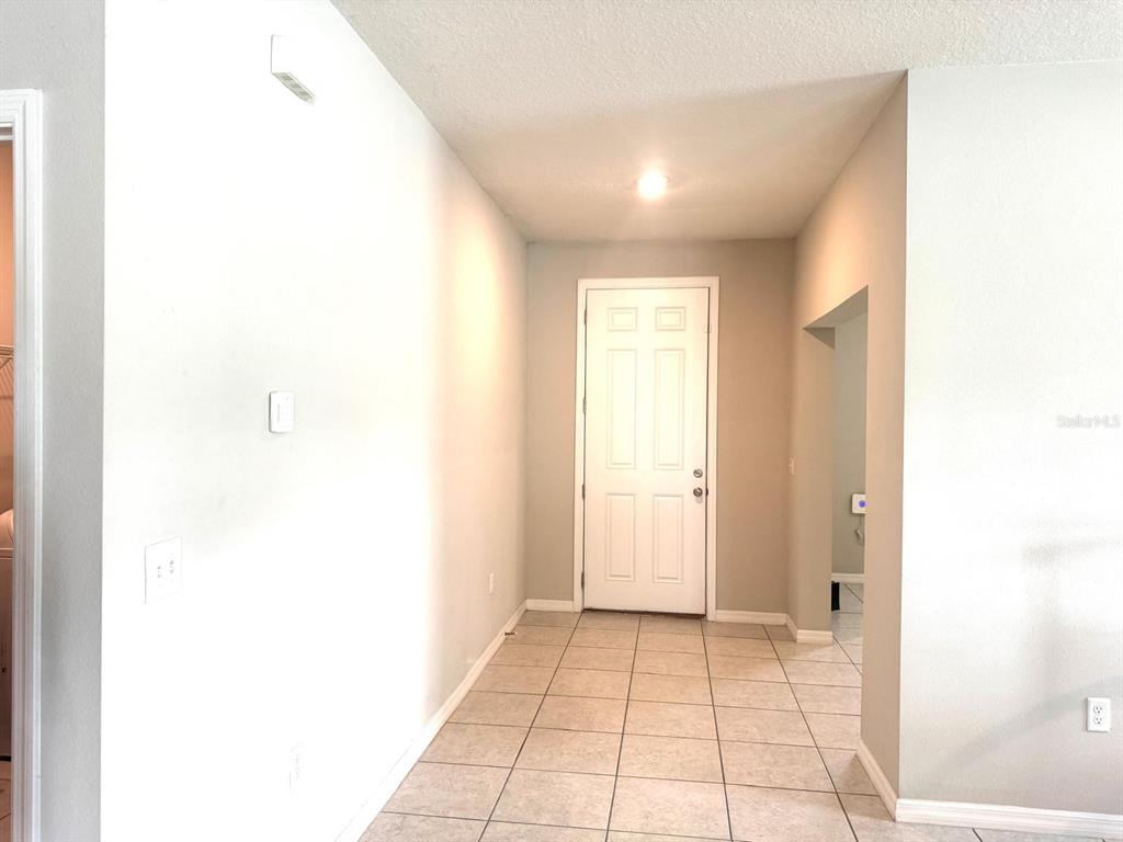A tiled entryway features a white front door and a doorway leading to a bathroom — 863 HUDSON VALLEY DRIVE, KISSIMMEE, FL