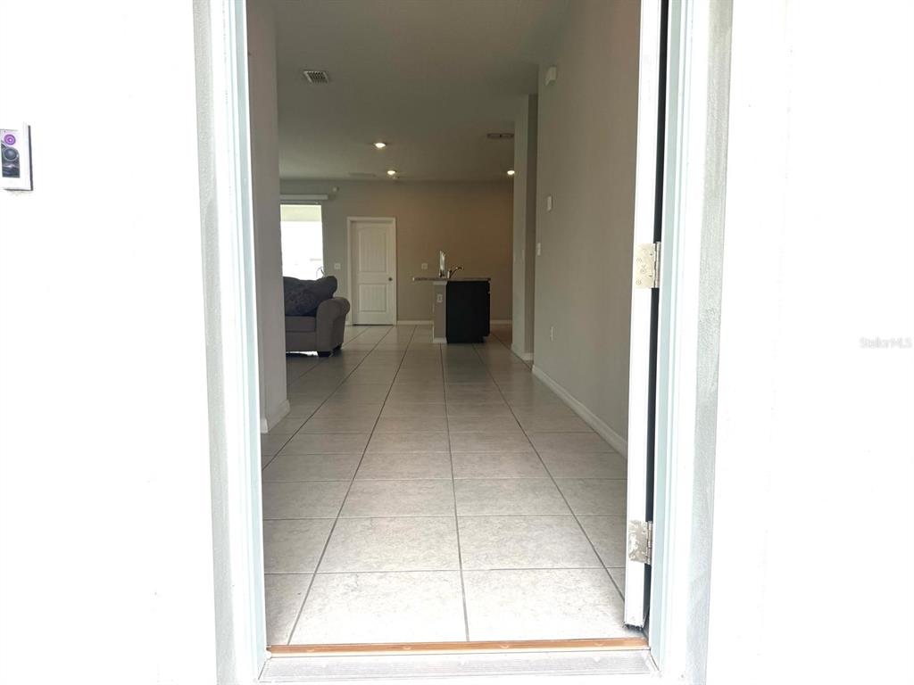 An entryway leads into an open-concept living area with tiled floors and a kitchen island — 863 HUDSON VALLEY DRIVE, KISSIMMEE, FL