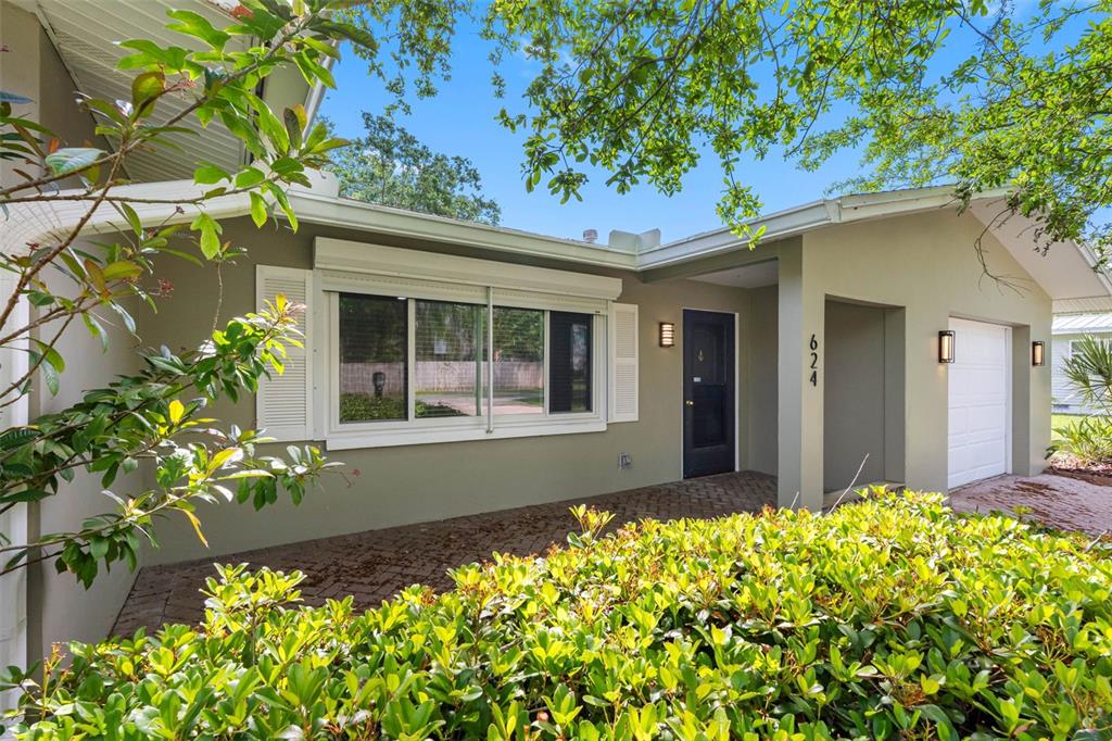 The exterior of a single-story house features a brick walkway, a dark front door, and shutters — 624 ORANGE STREET, PALM HARBOR, FL