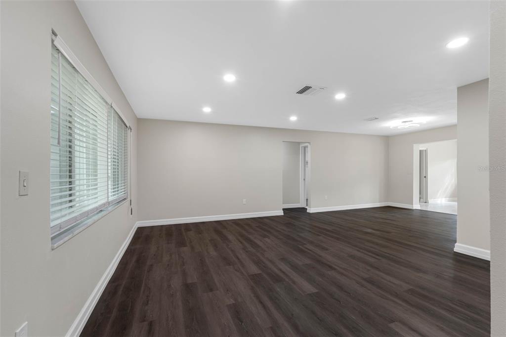 An empty room features dark wood-look flooring, light gray walls, and recessed ceiling lighting — 624 ORANGE STREET, PALM HARBOR, FL