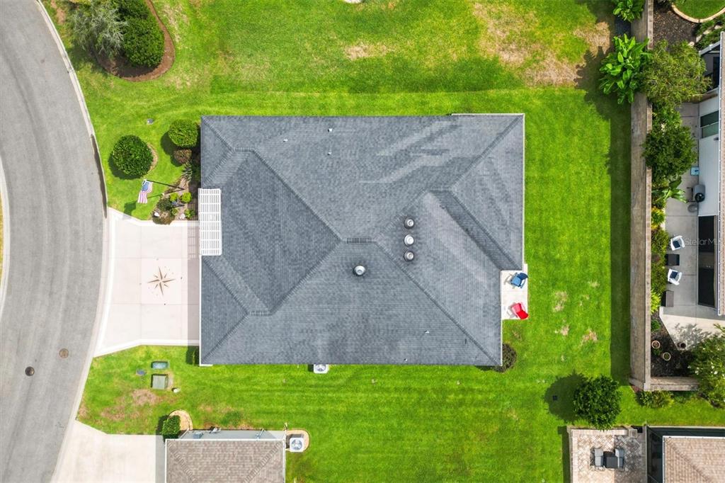 An aerial view shows a house with a gray shingled roof, driveway, and surrounding lawn — 5996 DELPHINA LOOP, THE VILLAGES, FL