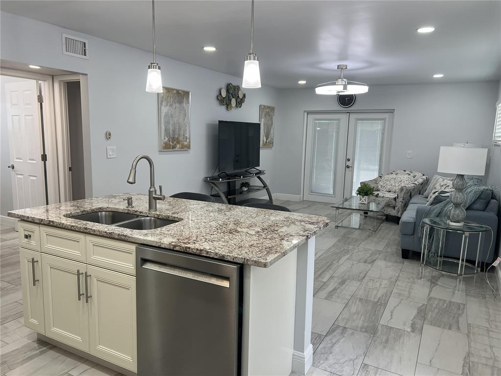 A kitchen features stainless steel appliances, off-white cabinets, granite countertops, and light-colored tile flooring — 1742 8TH STREET, SARASOTA, FL