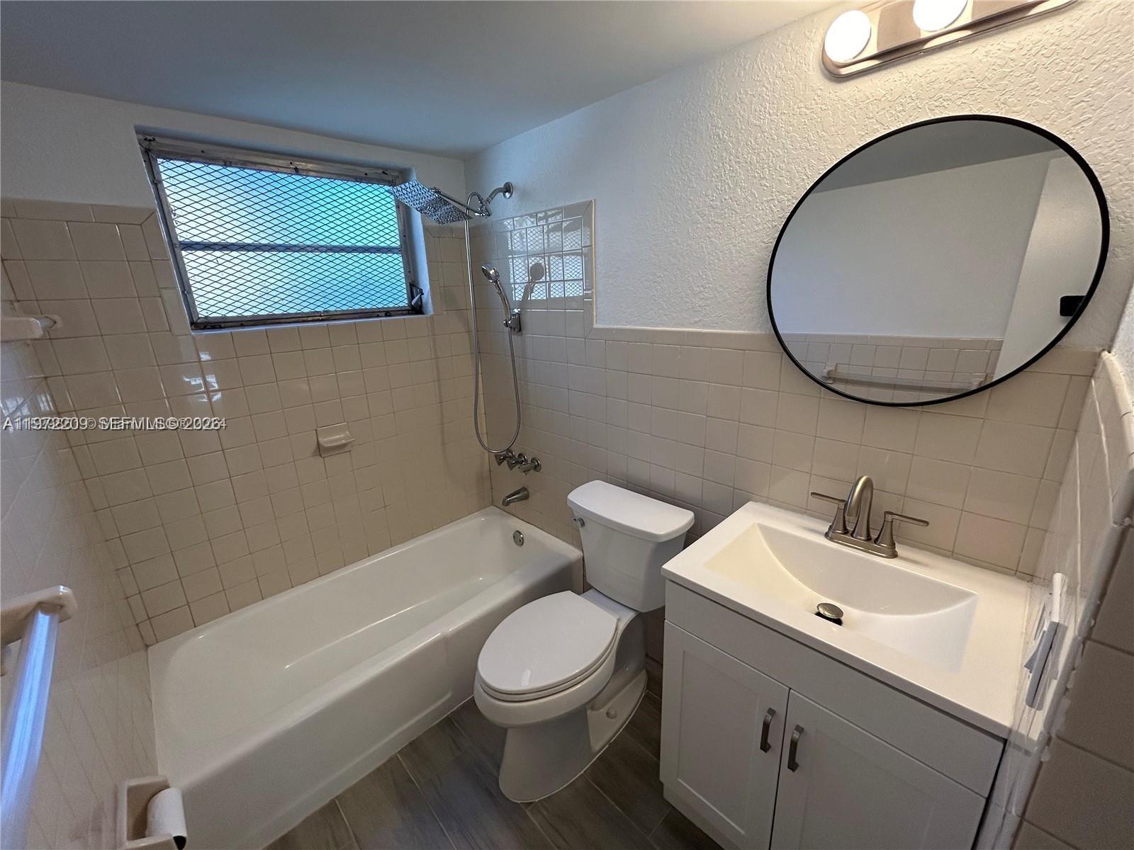 A bathroom features a white vanity, a toilet, and a bathtub with a shower head — 17 NE 2nd Ave # 108, Dania Beach FL 33004, DANIA BEACH, FL