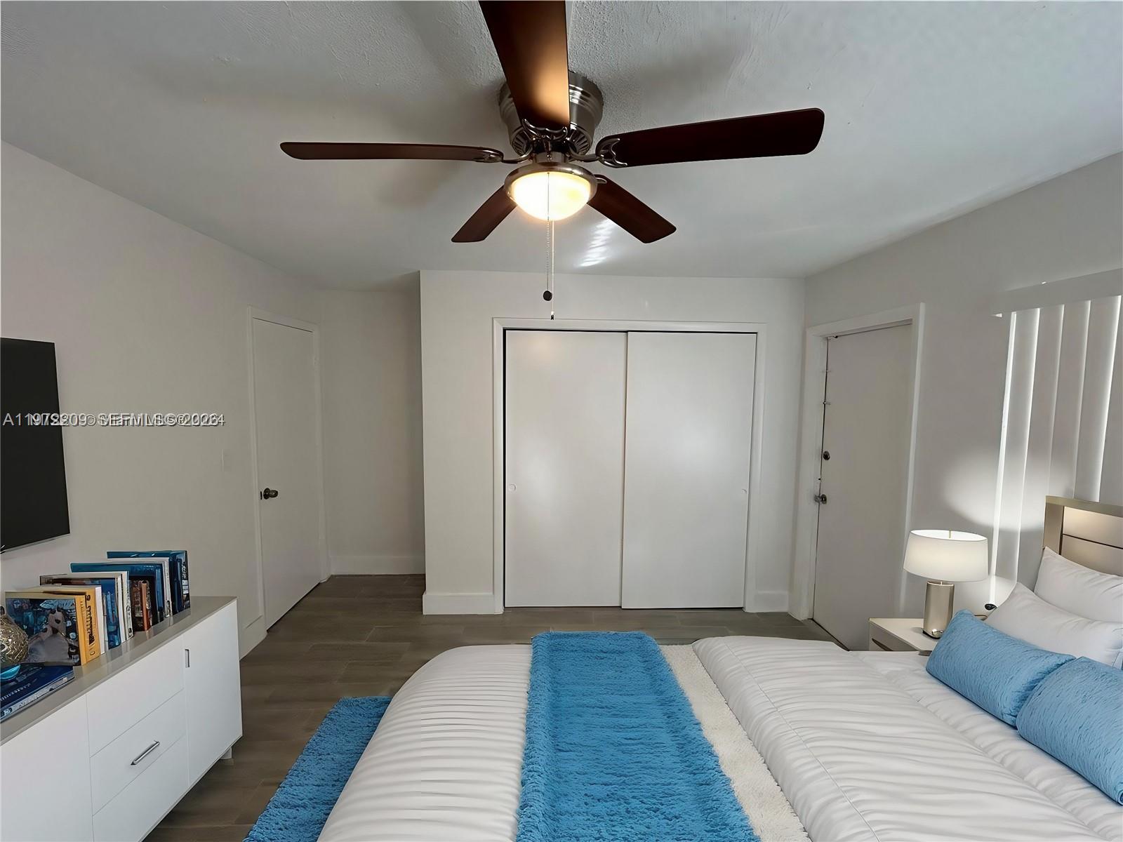 A bedroom features a ceiling fan, white walls, sliding closet doors, and a bed with blue accents — 17 NE 2nd Ave # 108, Dania Beach FL 33004, DANIA BEACH, FL