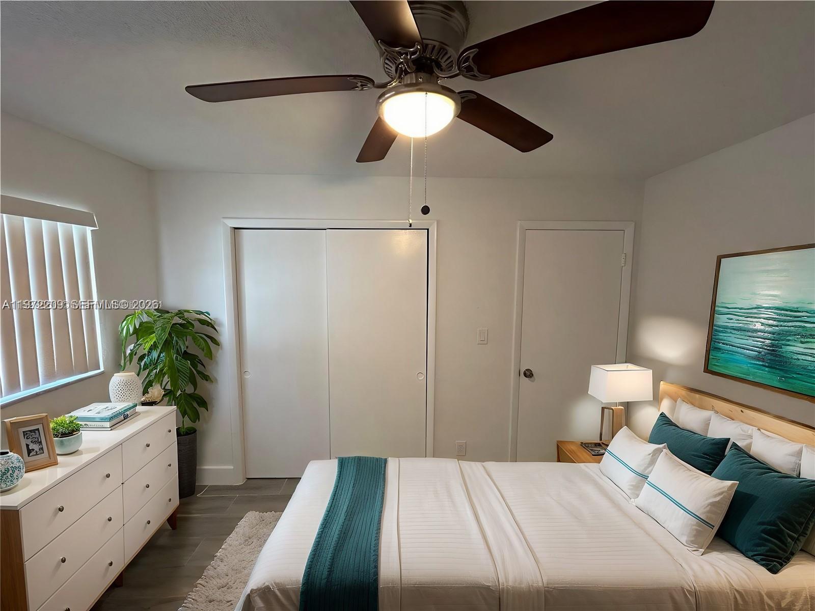 A bedroom features a bed with teal accents, a white dresser, and a ceiling fan — 17 NE 2nd Ave # 108, Dania Beach FL 33004, DANIA BEACH, FL