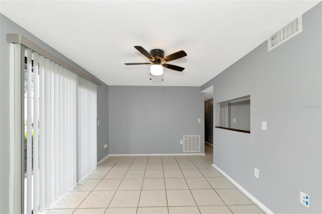 A dining area with light gray walls, tile flooring, a ceiling fan, and sliding glass doors — 5026 WATER OAK DRIVE UNIT 109, BRADENTON, FL