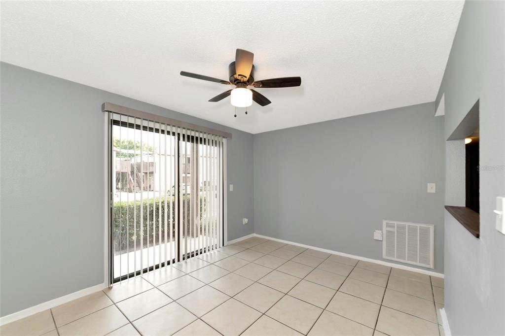 A dining area with gray walls, tile flooring, a ceiling fan, and sliding glass doors — 5026 WATER OAK DRIVE UNIT 109, BRADENTON, FL