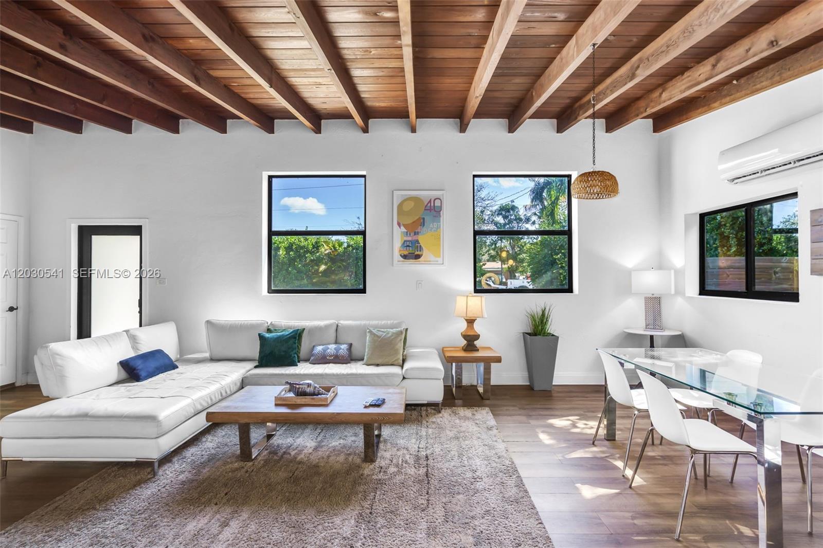 A living and dining area features a wood-beamed ceiling, white walls, and a sectional sofa — 11534 NE 13th Ave, Miami FL 33161, MIAMI, FL