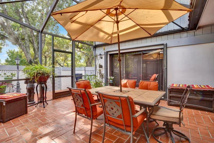A dining area features a glass table, rattan chairs, and large windows overlooking a patio — 10026 NW 52nd Ter, Doral FL 33178, DORAL, FL