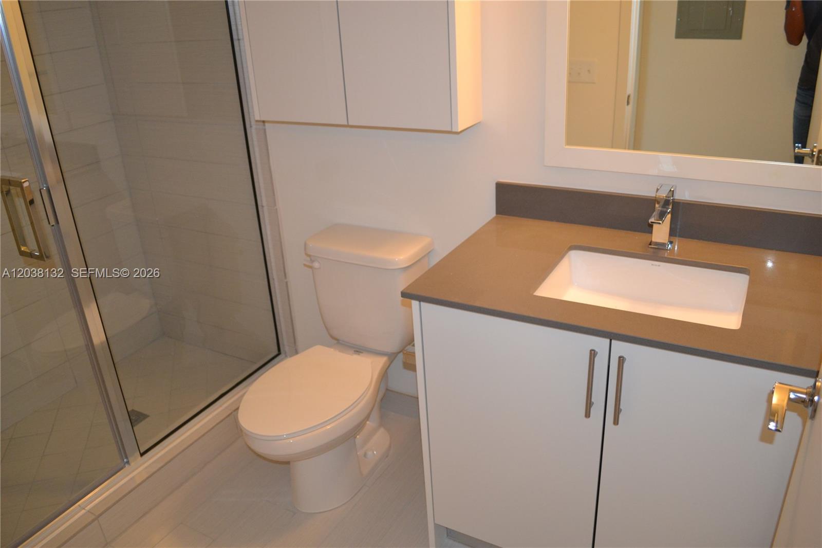 A bathroom features a glass-enclosed shower, a white toilet, and a vanity with a gray countertop — 999 SW 1st Ave # 3202, Miami FL 33130, MIAMI, FL